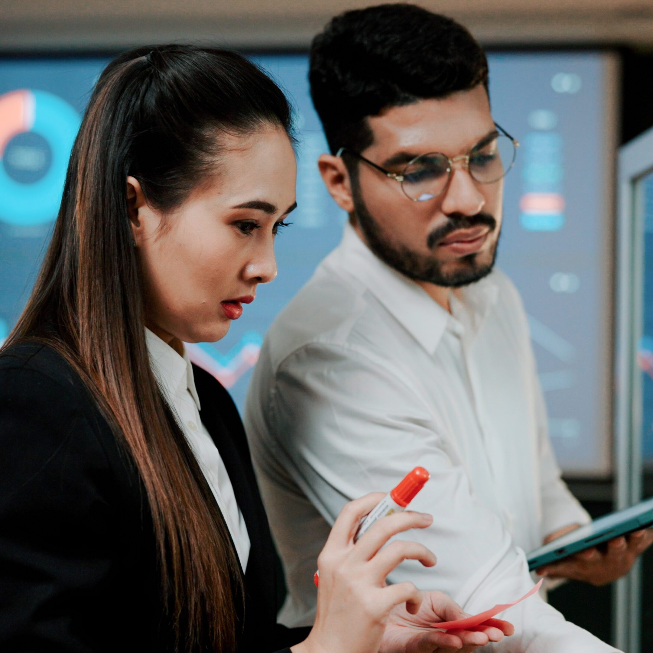 Young man and woman preparing visual aids on a writing board together before their team presentation started.